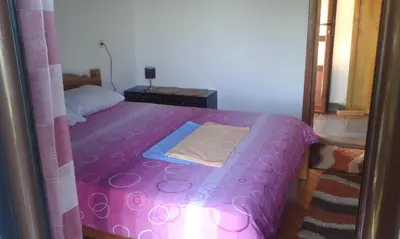 a small bedroom with a pink bed with a blanket at Draga`s rooms in Virpazar