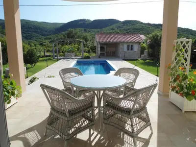 a patio with a table and chairs and a pool at Apartments Raskovic in Radanovići