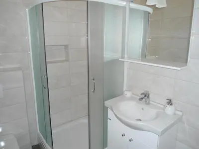 a white bathroom with a sink and a shower at Apartments Raskovic in Radanovići