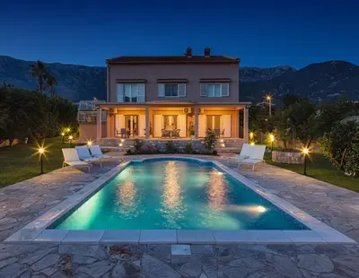 a villa with a swimming pool in front of a house at Apartments Raskovic in Radanovići