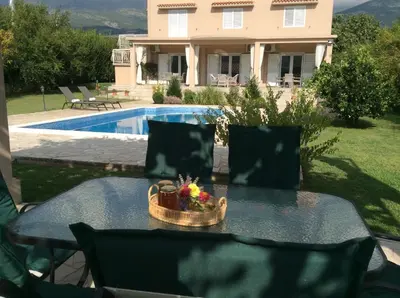 a table with a basket of flowers on it in front of a house at Apartments Raskovic in Radanovići