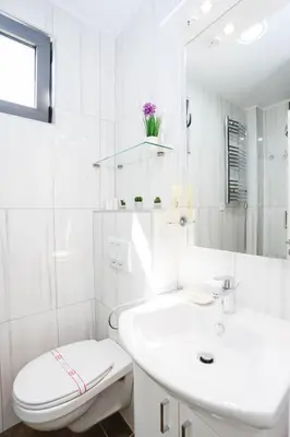 a white bathroom with a toilet and a sink at Hotel Arka in Budva