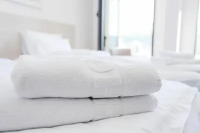 a stack of white towels on a bed at Hotel Arka in Budva