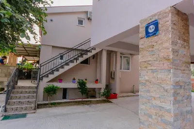a building with a staircase and a blue sign on a pillar at Paradise Bay Apartments in Kotor