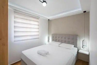 a bedroom with a large white bed with a window at Apartments Dali in Budva