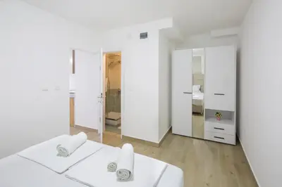 a white room with two beds and a mirror at Apartments Dali in Budva