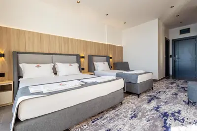 a hotel room with two beds and a chair at Continental Hotel in Ulcinj