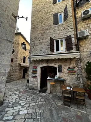 a stone building with a table in front of it at Athos Guesthouse in Kotor