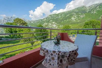 a table and chairs on a balcony with a view of mountains at Milas Trojica Kotor in Kotor