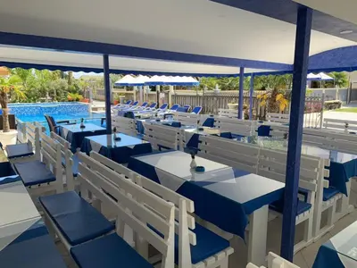 a restaurant with blue tables and chairs next to a pool at Spa Hotel Montefila in Ulcinj