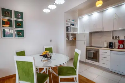 a kitchen with a white table and green chairs at Luxury Budva Center Apartments in Budva
