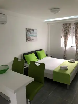 a bedroom with a bed and two green chairs at D&D Budva in Budva
