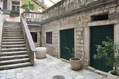 a stone building with green garage doors and stairs at Apartment Miguel in Kotor