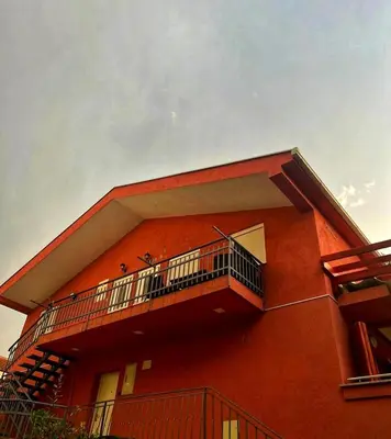 a red building with a balcony on the side of it at Apartmani Jankovic in Budva