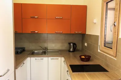 a kitchen with orange cabinets and a sink at De Lux Apartments in Petrovac na Moru