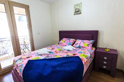 a small bedroom with a bed with a purple bedspread at De Lux Apartments in Petrovac na Moru