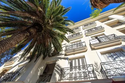 a white building with a palm tree in front of it at De Lux Apartments in Petrovac na Moru
