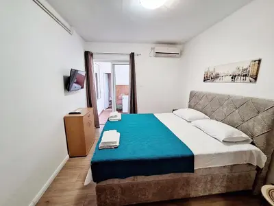 a bedroom with a large bed with a blue blanket at Apartmani Hortenzija in Budva