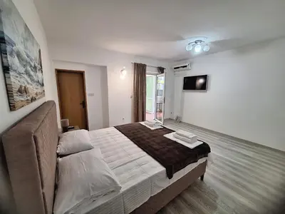 a bedroom with a large bed and a television at Apartmani Hortenzija in Budva