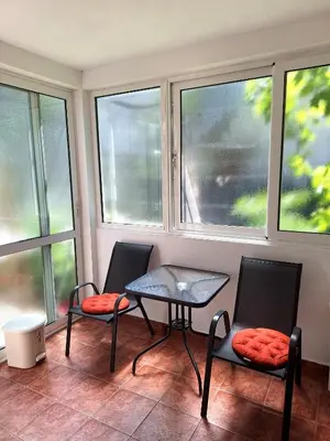 two chairs and a table in a room with windows at Apartmani Hortenzija in Budva