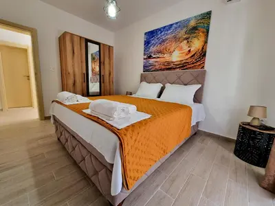 a bedroom with a large bed with an orange blanket at Apartmani Hortenzija in Budva