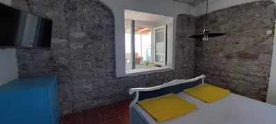 a room with a table with yellow cushions and a television at Beach House Buljarica in Petrovac na Moru