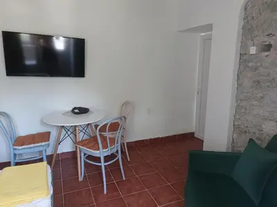 a room with a table and chairs and a tv on the wall at Beach House Buljarica in Petrovac na Moru