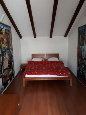 a bedroom with a bed with red sheets and wooden floors at Apartment Sasha in Kotor