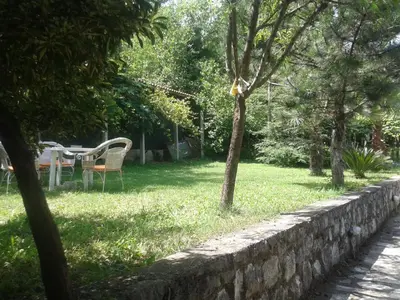 a table and chairs in a yard next to a stone wall at Apartment Sasha in Kotor