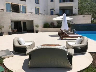 a patio with chairs and an umbrella and a pool at Villa Hedonism in Sveti Stefan