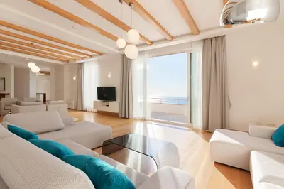 a living room with white furniture and a view of the ocean at Villa Hedonism in Sveti Stefan