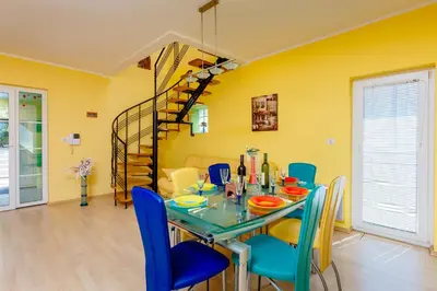 a dining room with a table and chairs and a spiral staircase at Spacious Central Magik in Kotor