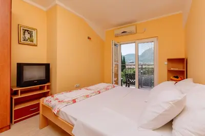 a bedroom with a bed and a television and a balcony at Spacious Central Magik in Kotor