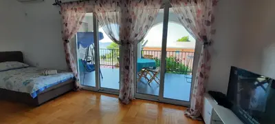 a room with a balcony with a bed and a television at Apartments Pines in Bar