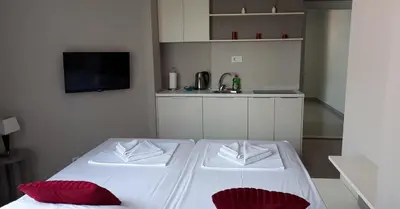 a white bed with red pillows in a room at Twister Apartments in Budva