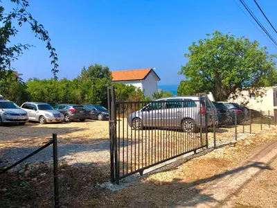 a fence with cars parked in a parking lot at Open Sea Apartments in Utjeha