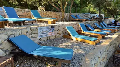 a row of blue lounge chairs on a stone wall at Arabela 2 Apartments in Utjeha