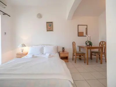 a bedroom with a white bed and a table and chairs at Mediterranean Guest House Balkan in Budva