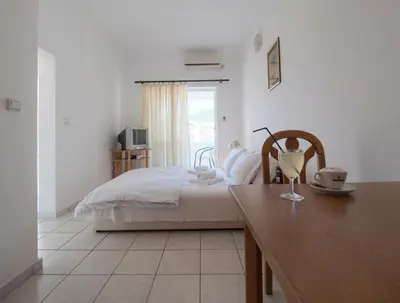 a bedroom with a bed and a table and a window at Mediterranean Guest House Balkan in Budva