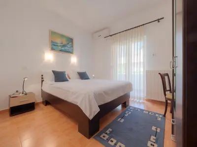 a bedroom with a bed and a chair in it at Mediterranean Guest House Balkan in Budva