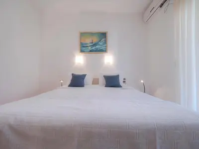 a white bedroom with a large white bed with blue pillows at Mediterranean Guest House Balkan in Budva
