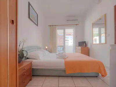 a bedroom with a bed with an orange blanket at Mediterranean Guest House Balkan in Budva