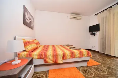 a bedroom with a bed and a desk and a television at MG apartments and rooms in Budva
