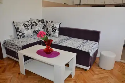 a living room with a couch and a table with flowers at MG apartments and rooms in Budva