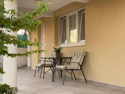 a patio with two chairs and a table and a window at Dajkovic Apartmani in Bar