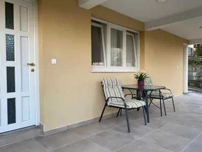 a patio with a table and chairs and a window at Dajkovic Apartmani in Bar