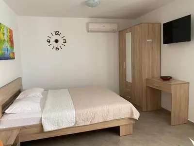 a bedroom with a bed and a clock on the wall at Dajkovic Apartmani in Bar