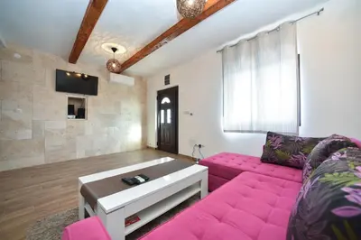 a living room with a pink couch and a table at Villa Old Olive 2 in Budva