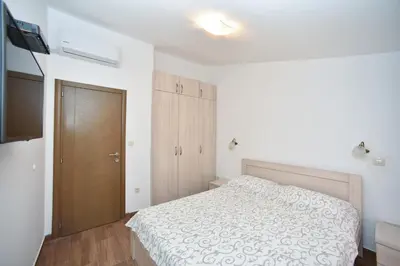 a white bedroom with a bed and a television at Villa Old Olive 2 in Budva