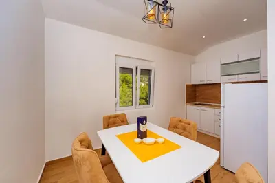 a kitchen and dining room with a white table and chairs at Apartment Stojanovic in Bar